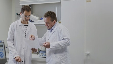 Two scientists in the lab talking and lookong into a paper