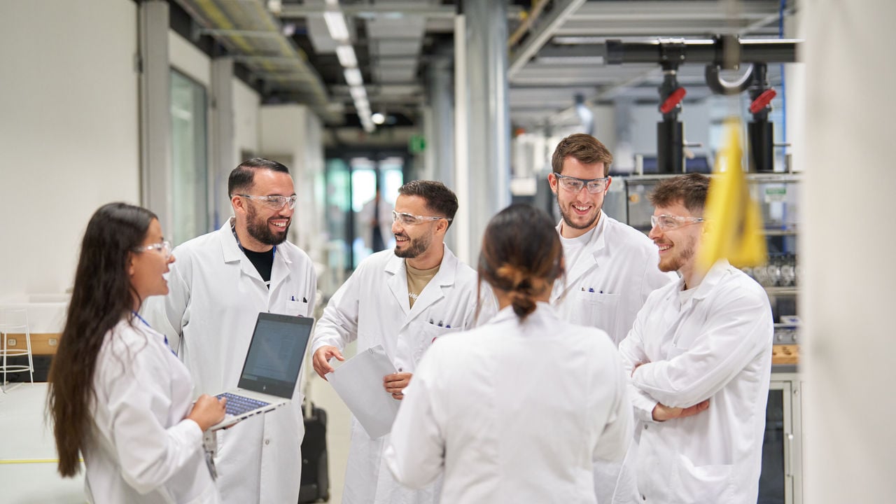 Group of scientitist in lab coats talking and laughing