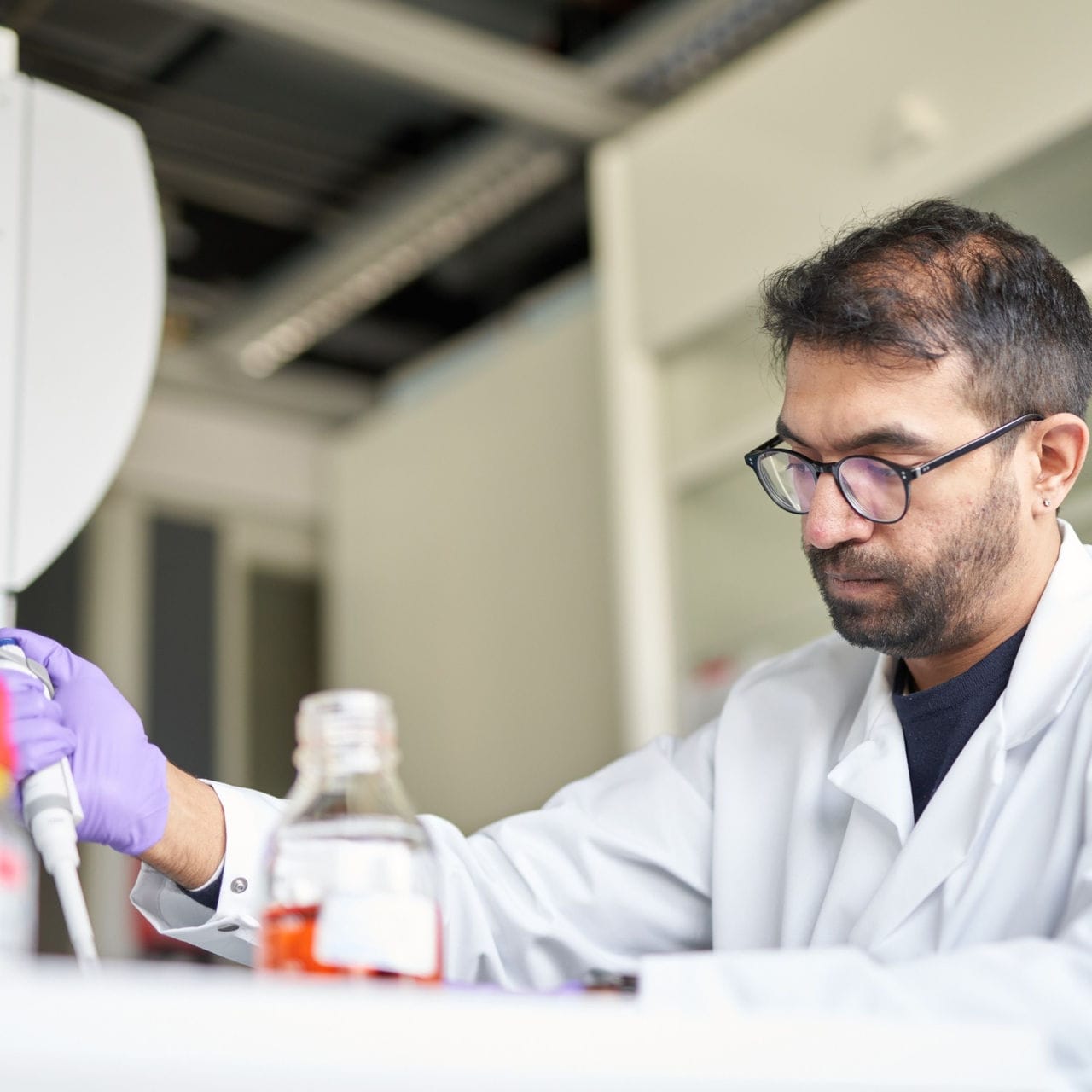 A scientist in a white lab coat conducting research.
