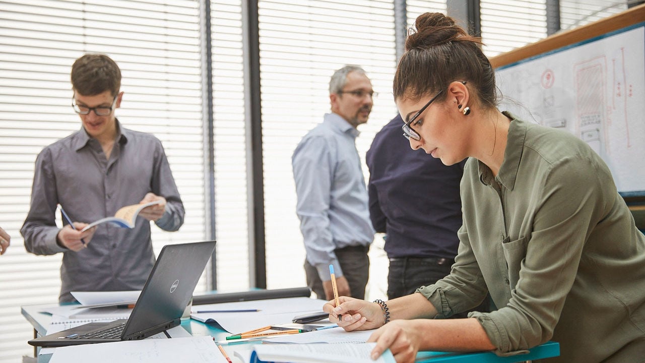 People at the meeting and the Cube working with a data on blackboard and laptop