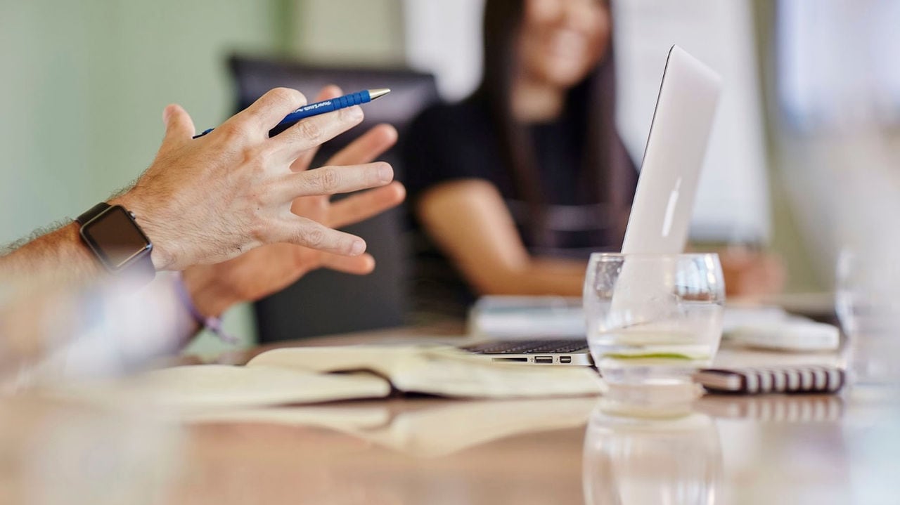 A person holds a pen in his hand while making a hand gesture during the meeting.