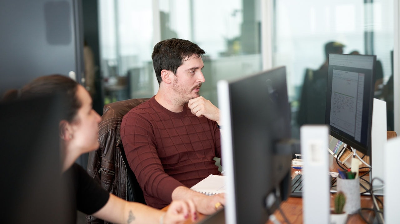 Two coworkers sitting at their desks, focused on their computer screens.