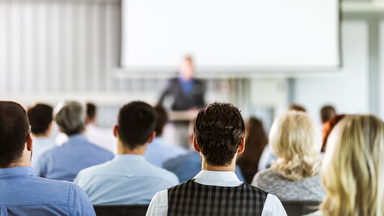 Back view of entrepreneurs having a training class in a board room. Focus is on man in the middle.