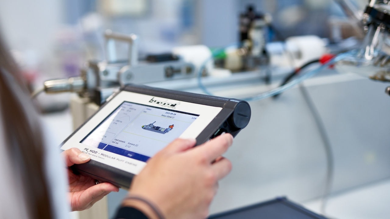 A scientist in laboratory holds a tablet with some data on it.