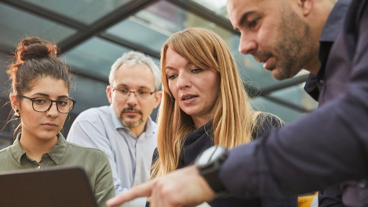 Group of people gathered around and looking at a computer.