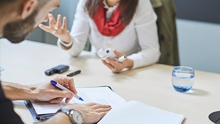 Two people talking about smoke-free products and taking notes.