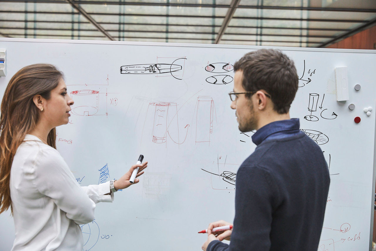 Man and women standing in front of the whiteboard with some sketches.