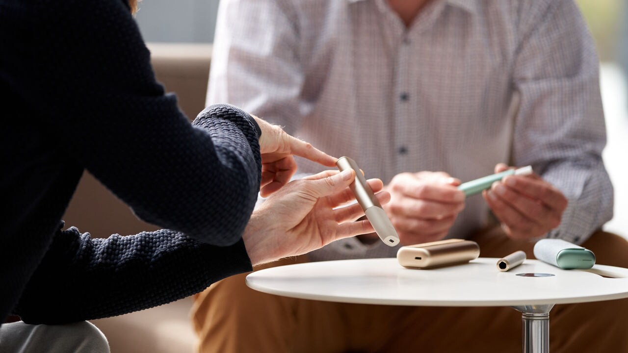 Two people sitting at a table, discussing smoke-free products.