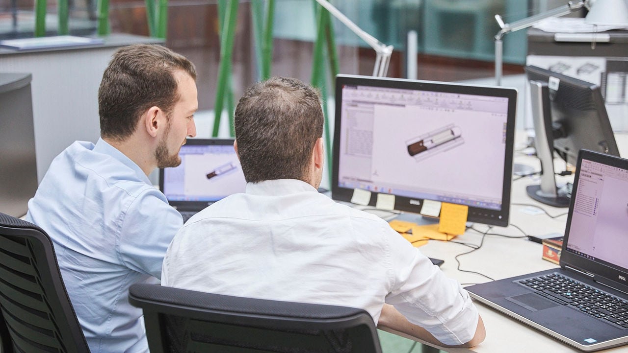 Two men talking while looking at the laptop