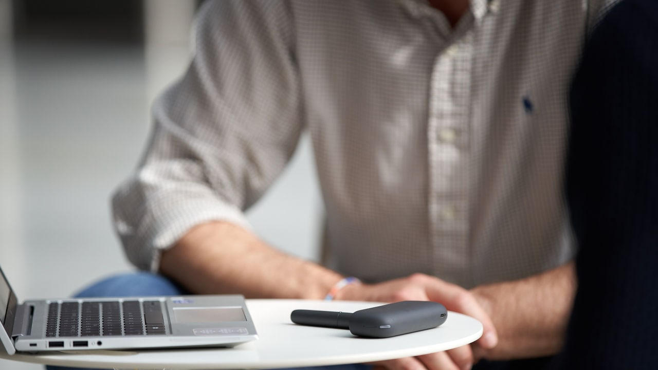 Smoke-free device stands on a coffee desk next to a computer.
