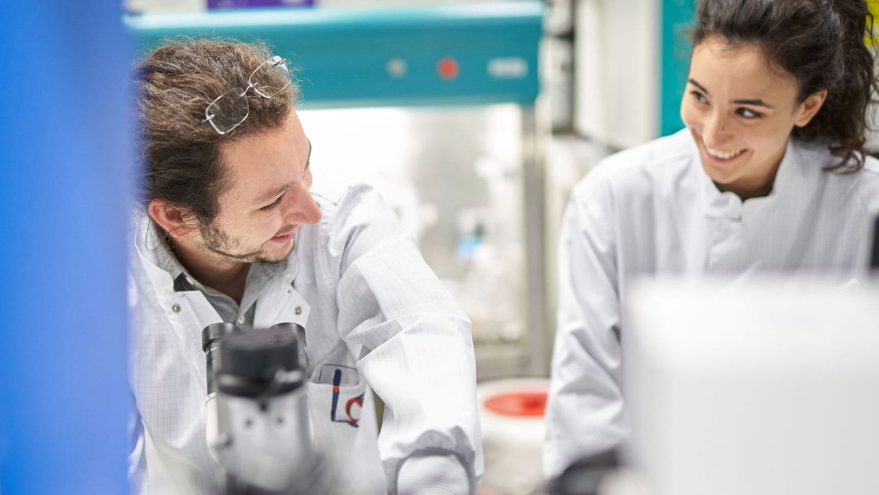Female and male scientists working and smiling in the PMI laboratory, Cube
