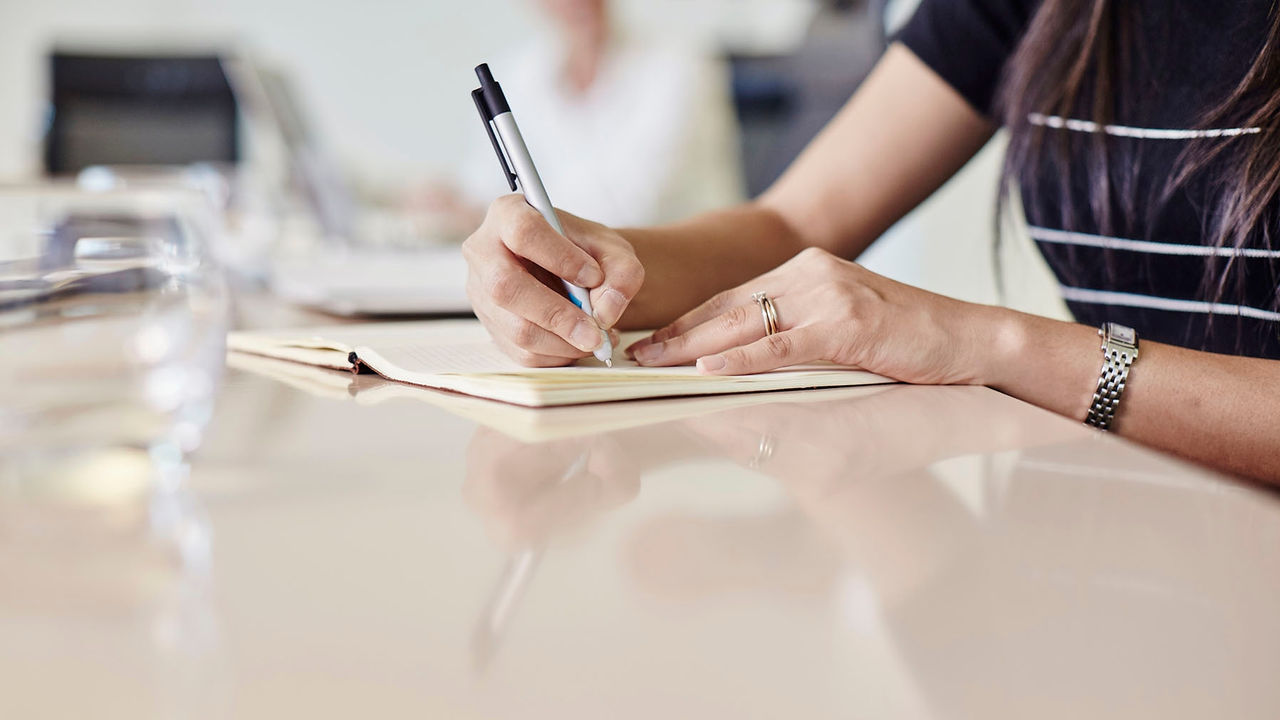 Women's hand taking notes during a meeting.
